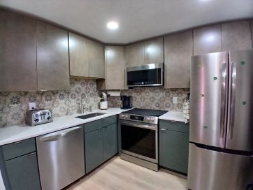 Modern kitchen with stainless steel appliances and floral backsplash.