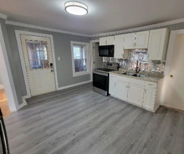 Modern kitchen with gray walls and white cabinetry.