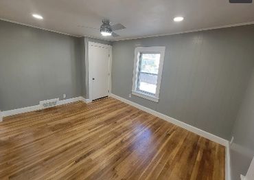 Empty room with gray walls and wooden floor.