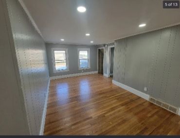 Empty room with hardwood floors and gray walls.
