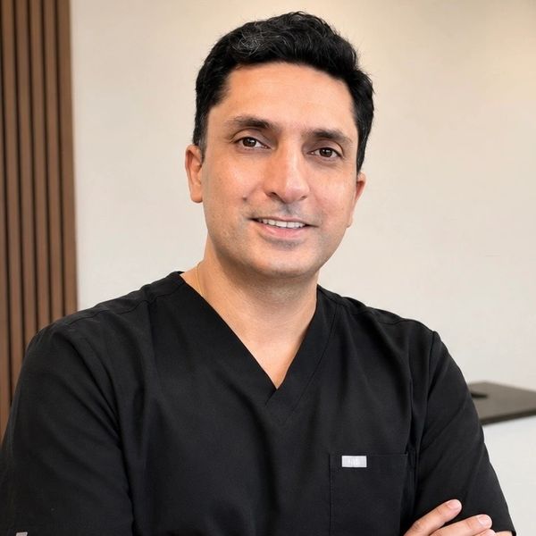 Dr. Rohit Basson, lead dentist at Smile Now Dental Studio in Pasadena, CA, smiling in black scrubs