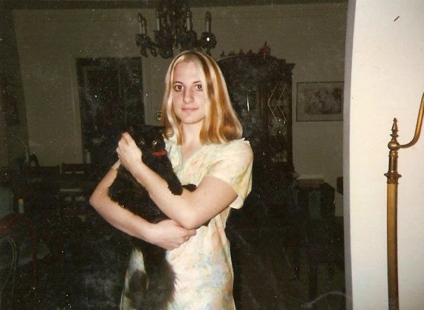16 year old Renee with the cool hair stands holding her black long hair cat.
