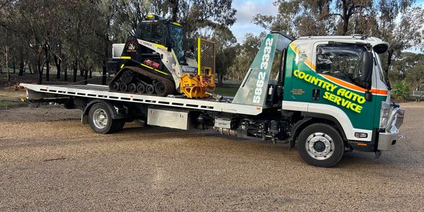 Tow truck carrying a small tracked vehicle.