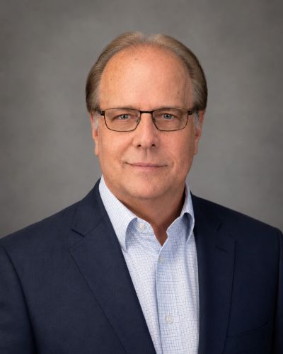 Professional headshot of a middle-aged man in glasses and a suit jacket.