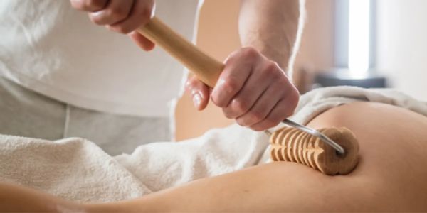 Person receiving a wooden massage therapy on their back.