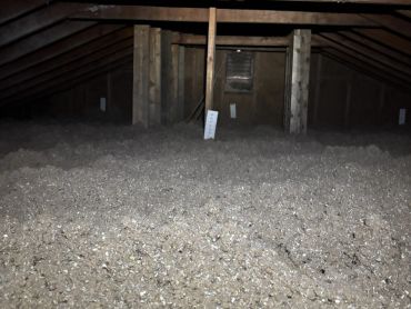 Dimly lit attic with wooden beams and insulation.