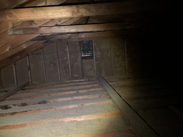 Dark attic with wooden beams and insulation.