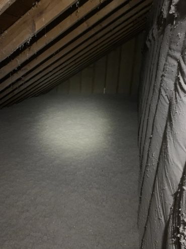 Attic space with insulation and wooden beams.