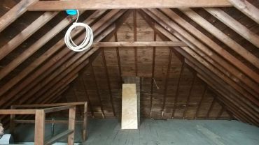 Empty wooden attic with beams and a coiled cable.