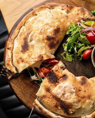 Cheesy calzone with fresh salad on a wooden board.