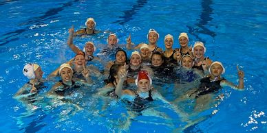 A group of water polo players posing in a pool.