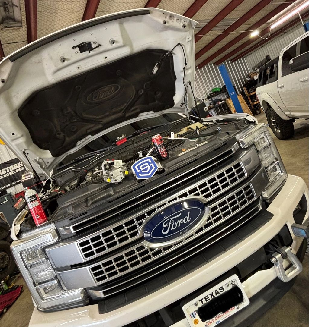 Ford truck with open hood in a garage undergoing maintenance.