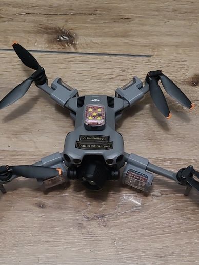 A compact drone with foldable propellers resting on a wooden surface.