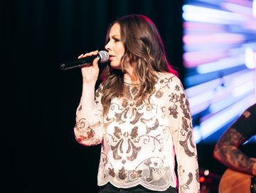 Woman singing on stage holding a microphone.