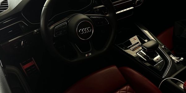 Dark Audi car interior with red leather seats.