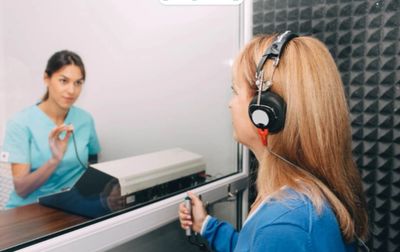 A woman undergoing a hearing test with an audiologist.