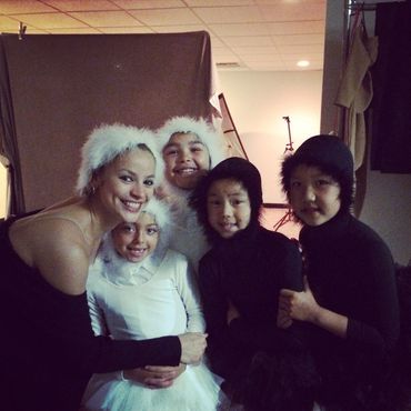 Group of children and an adult in black and white costumes, smiling for a photo.