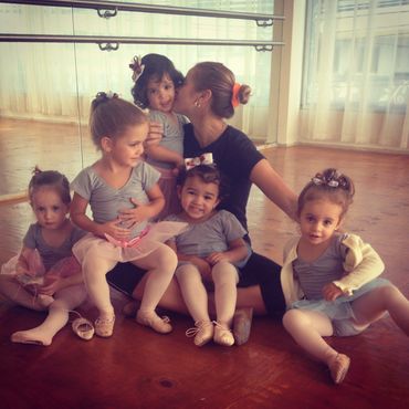 Young ballet students with their instructor in a dance studio.