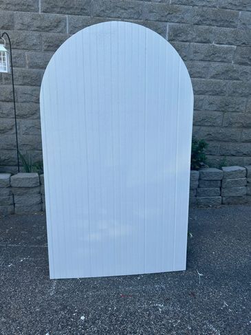 White wooden board with rounded top outdoors.