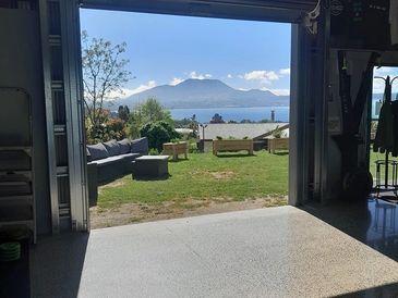 View from a garage opening to a grassy yard and distant mountains across water.