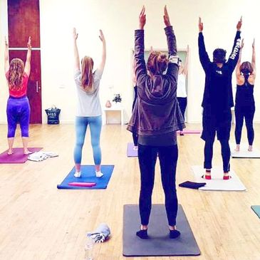 Group yoga session with participants raising arms.