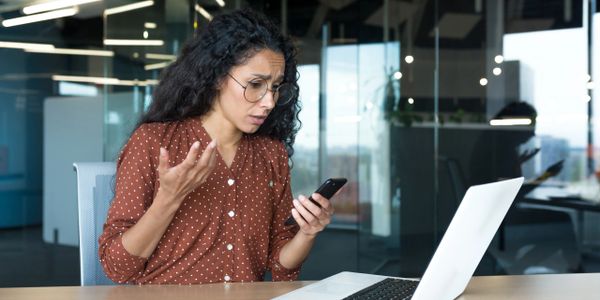 Woman frustrated while looking at her phone in an office.