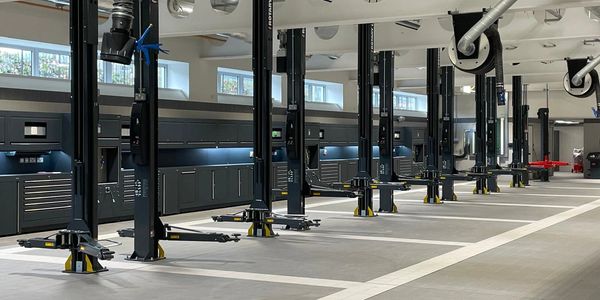 A clean, modern automotive workshop with multiple vehicle lifts and organized tool storage.