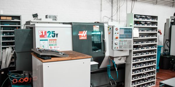 Haas ST-25Y CNC lathe machine in a workshop with organized shelves.