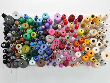 Colorful yarn spools on a pegboard.