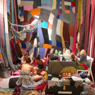 Four people in a colorful fabric-filled room.