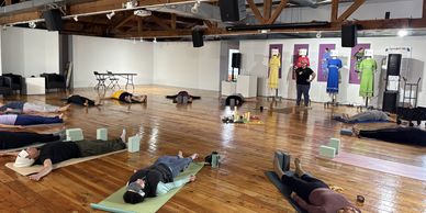 People lying on mats in a spacious studio for relaxation or yoga.