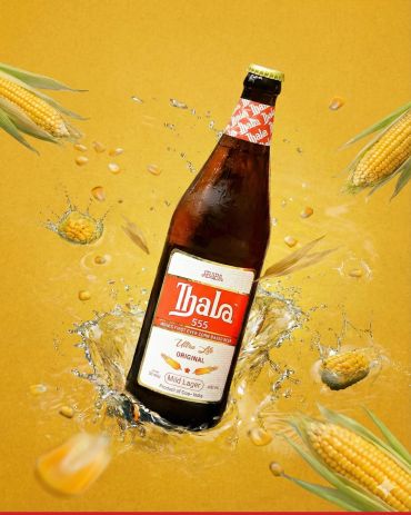 Bottle of Thala corn-based beer splashing with corn kernels.