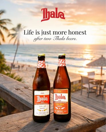 Two Thala beer bottles on a beachside table at sunset.