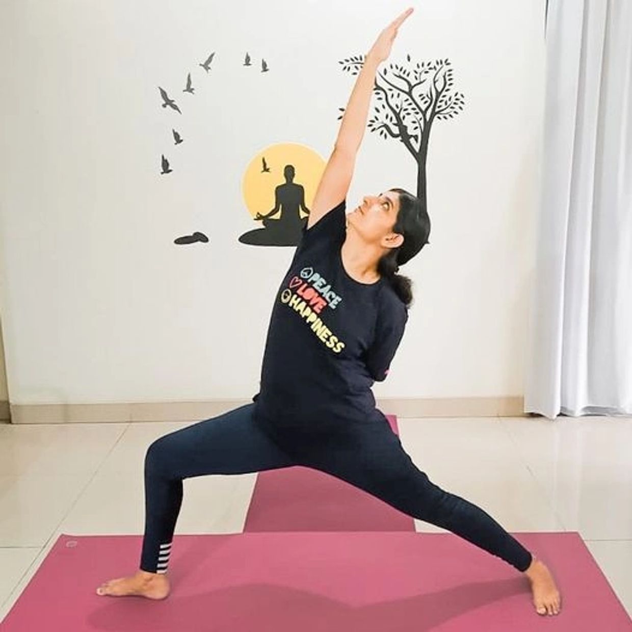 Woman practicing yoga indoors on a mat with motivational wall art.