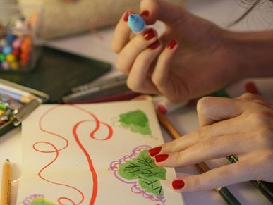 Person coloring in a book with markers and colored pencils.