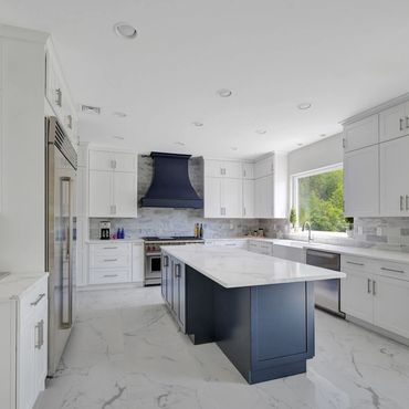 Modern kitchen with white cabinets and a navy island.