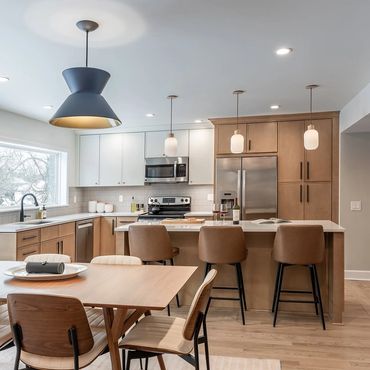 Modern kitchen with wood cabinetry, island seating, and stylish lighting.
