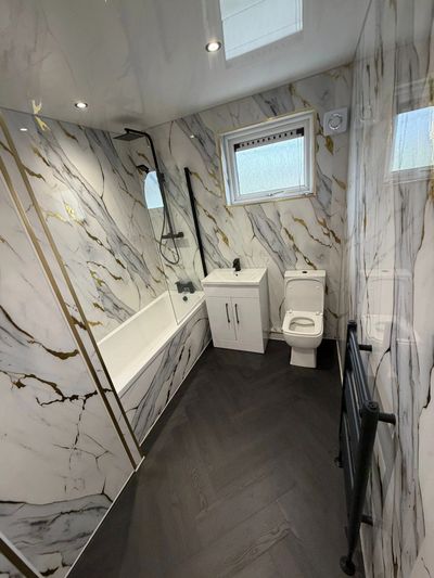 Modern bathroom with marble walls, black fixtures, and dark flooring.