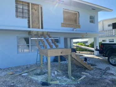 Wooden staircase under construction at a remodel with new doors and windows.