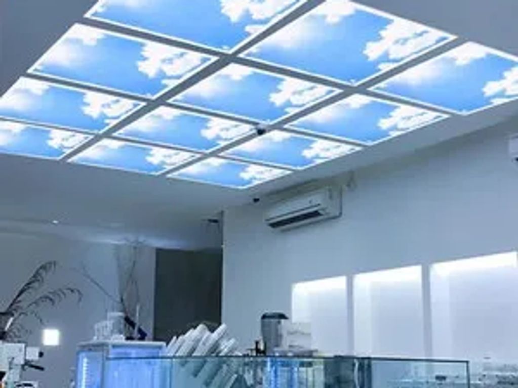 Bespoke office lighting installation with sky-effect ceiling panels, enhancing workspace ambience