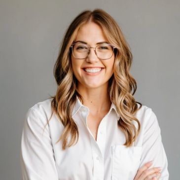 Smiling woman with glasses in white shirt.