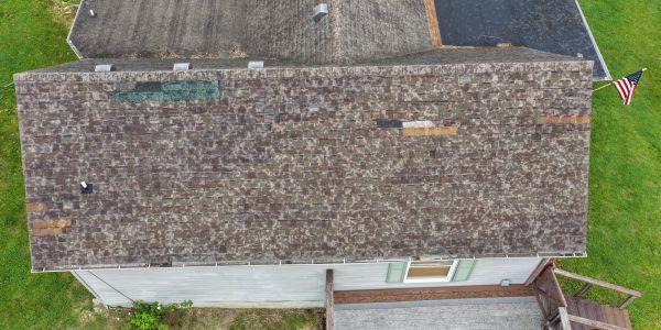 Overhead view of a worn roof on a house with a deck and flag.