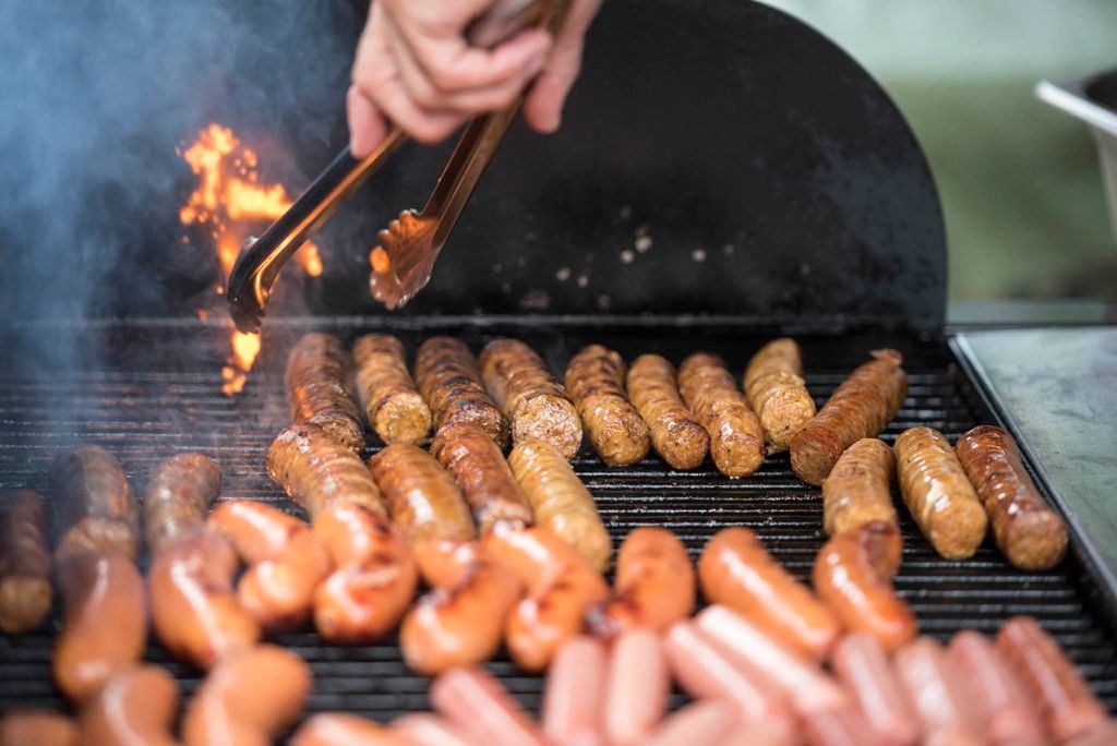 Grilling various sausages over an open flame.