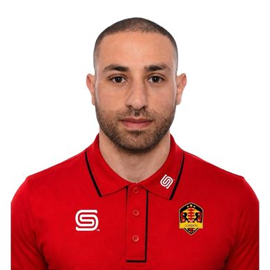 Man in a red sports polo with logos, looking at the camera.