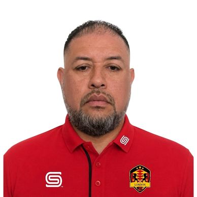 Man with short hair and beard wearing a red polo shirt with logos.