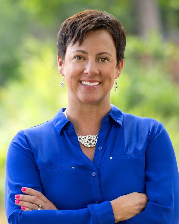 Confident woman in blue shirt smiling outdoors.