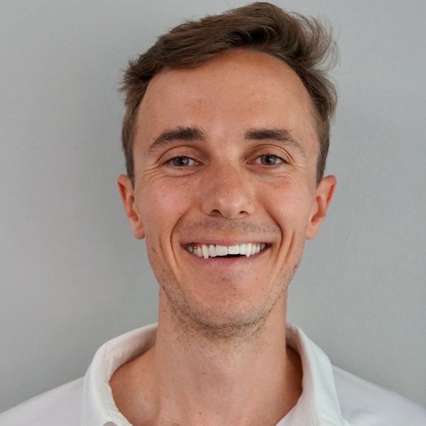 Smiling man in a white Master Wellness polo shirt against a plain background.