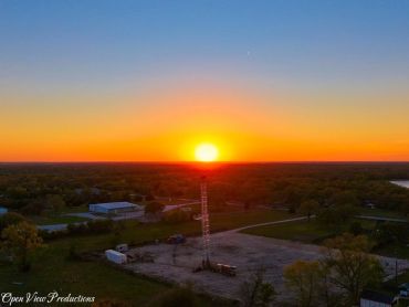 Sunset over a rural landscape with a tall tower at the center.