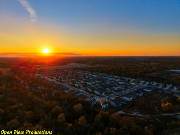 Sunset over a suburban neighborhood with houses and trees.