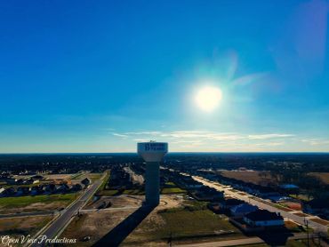 Water tower in Bryan, Texas under a bright sun and clear blue sky.